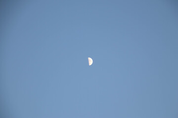 Half moon during day time on a blue sky. Copy space.
