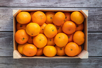 a crate with ripe orange tangerines on a wooden table top view - 395142293