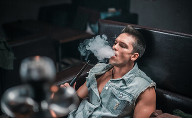 A man of European appearance exhales smoke in the hookah bar.