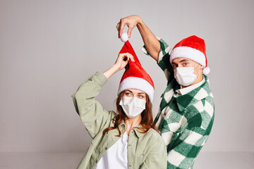 Family couple in medical masks on the face of Santa hat New Years winter hugs