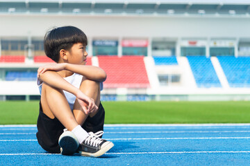 young Asian boy sitting on a blue track