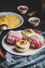 Preparing of bacon-wrapped button mushrooms stuffed with grated cheddar cheese and spices