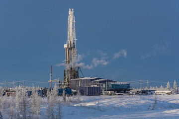 Winter landscape of a taiga forest with a drilling rig at the Northern oil and gas field....