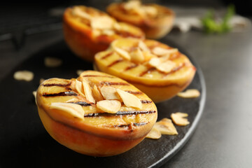 Delicious grilled peaches with almond flakes on grey table, closeup