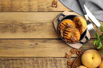 Delicious grilled peaches with walnuts on wooden table, flat lay. Space for text