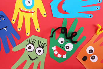 Funny hand shaped monsters on red background, flat lay. Halloween decoration