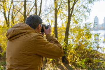 Professional male photographer taking outdoor photo in fall forest.