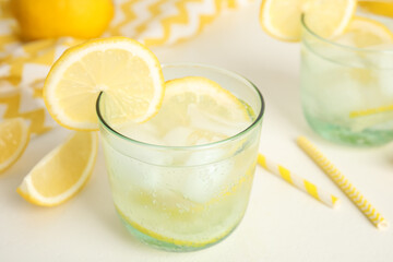 Soda water with lemon slices and ice cubes on white table