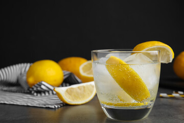 Soda water with lemon slices and ice cubes on grey table. Space for text