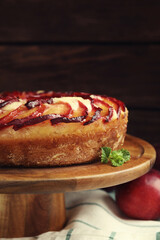 Delicious pie with plums on wooden cake stand, closeup