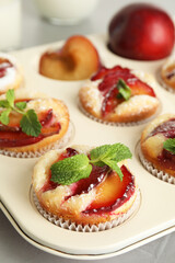 Delicious cupcakes with plums in baking pan, closeup