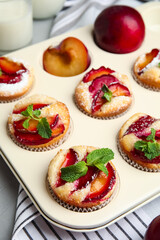 Delicious cupcakes with plums in baking pan