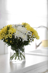 Vase with beautiful chrysanthemum flowers on countertop in kitchen. Interior design