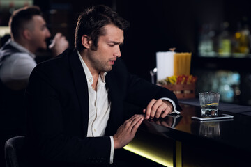 a young man drank a lot at the bar, sitting drunk at the bar with a cocktail.