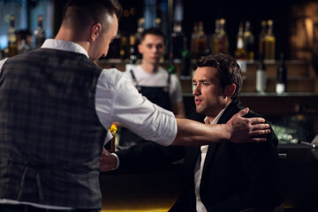 two male friends meet at the bar at the counter and communicate.