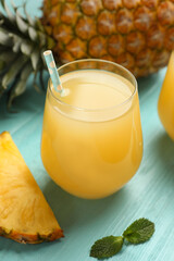 Delicious fresh pineapple juice on light blue wooden table