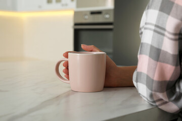 Woman with pink cup at table indoors, closeup