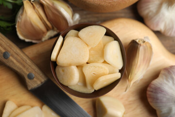 Fresh sliced garlic cloves in bowl on wooden table, flat lay. Organic product