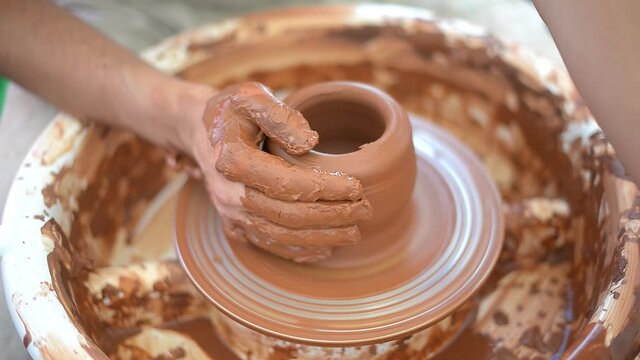 Potter master woman shows how to work with clay and pottery wheel. Hand work. Close-up.