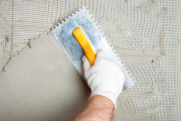 Embedding the fiberglass mesh on the thermal insulation boards and then smoothing the adhesive mortar with a notched trowel. - 395148292