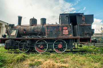 An old rusty locomotive in front of the main train station of the city.