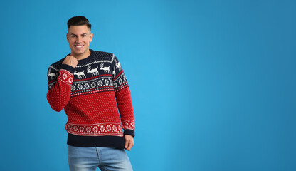 Handsome man in Christmas sweater on blue background