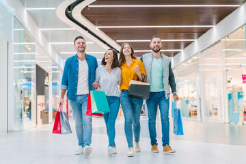 Group of young stylish friends spending day-off together doing shopping