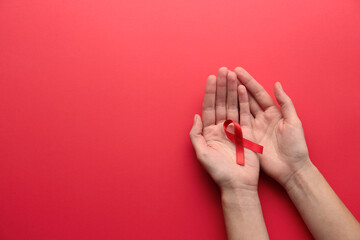 Woman holding red awareness ribbon on color background, top view with space for text. World AIDS disease day
