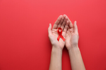 Woman holding red awareness ribbon on color background, top view with space for text. World AIDS...