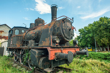 Fototapeta na wymiar An old rusty locomotive in front of the main train station of the city