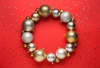 Beautiful festive wreath made of color Christmas balls on red background, top view