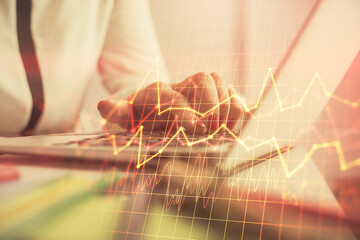 Double exposure of businesswoman hands typing on computer and financial graph hologram drawing. Stock market analysis concept.