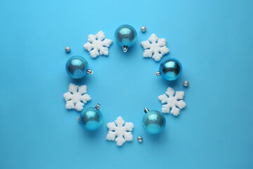 Bright festive wreath made of Christmas balls and decorative snowflakes on light blue background, top view. Space for text