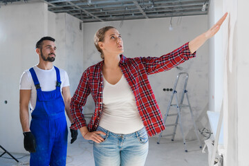 The male worker shows the woman the renovation of the apartment. She is unhappy