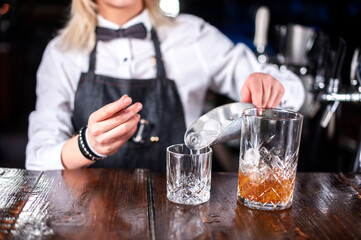 Girl barman formulates a cocktail in the beerhouse