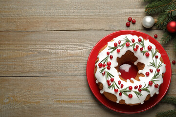 Flat lay composition with traditional Christmas cake and decorations on wooden table, space for text