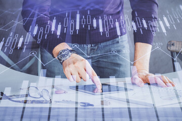 Double exposure of man's hands holding and using a digital device and forex graph drawing. Financial market concept.