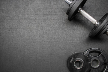 Naklejka na ściany i meble Barbell and dumbbells on the floor at the gym. Top down view flat lay with bodybuilding equipment on a black background and empty space for text. Fitness, weight training or healthy lifestyle concept