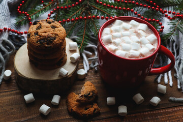 Christmas flat lay with hot chocolate, marshmallows, cookies on wooden stand, and Christmas tree branches. Cozy winter home postcard with selective focus. Festive Christmas hot drinks. Close-up