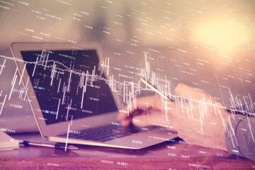 Double exposure of man's hands holding and using a digital device and forex graph drawing. Financial market concept.