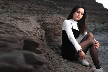 Girl posing with a black and white dress at a rocky cove of the basque coast.