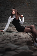 Girl posing with a black and white dress at a rocky cove of the basque coast.