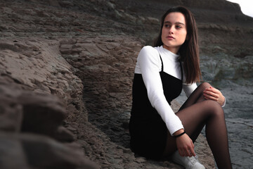 Girl posing with a black and white dress at a rocky cove of the basque coast.