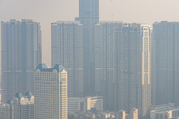 Tall buildings in industrial city with hazy polluted smog 