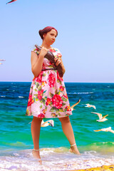 A smiling woman in a pink dress holding a large brown flathead catfish.