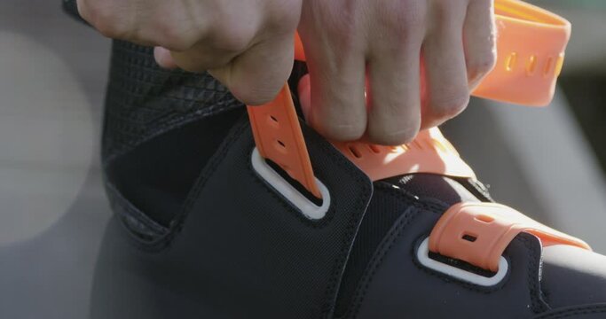 Young man tightens wakeboard boots, prepares for a wakeboarding session.