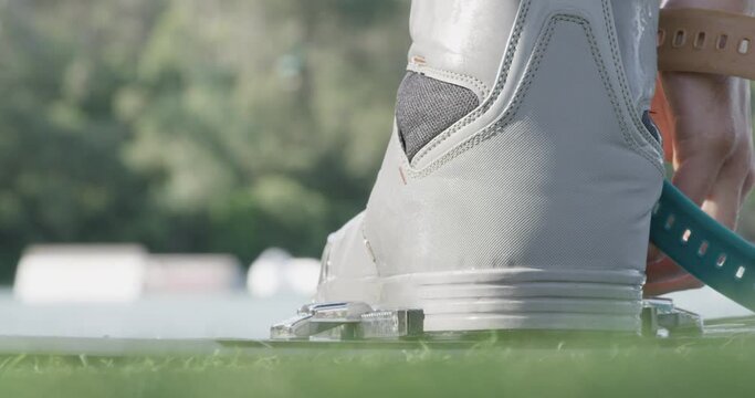 Young man tightens wakeboard boots, prepares for a wakeboarding session.