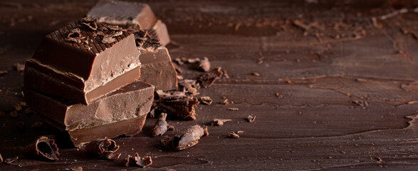 Organic food snack tasty sweet dessert milk dark chocolate bar macro closeup broken slide piece and fruit orange raspberry hazelnut nuts on cocoa cacao powder wooden table for new year Christmas gift