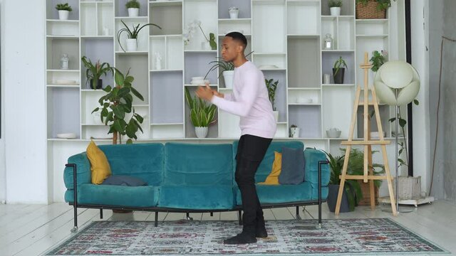 African man dancing in his living room. A young dancer walks across the living room and dances.
