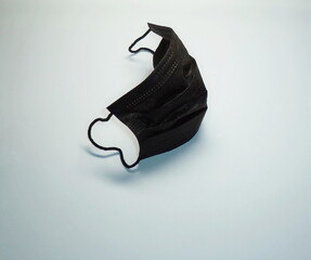 Black medical mask on a light background. COVID-19 Pandemic Coronavirus, hygienic and preventive protection. Health, medicine and pandemic concept.